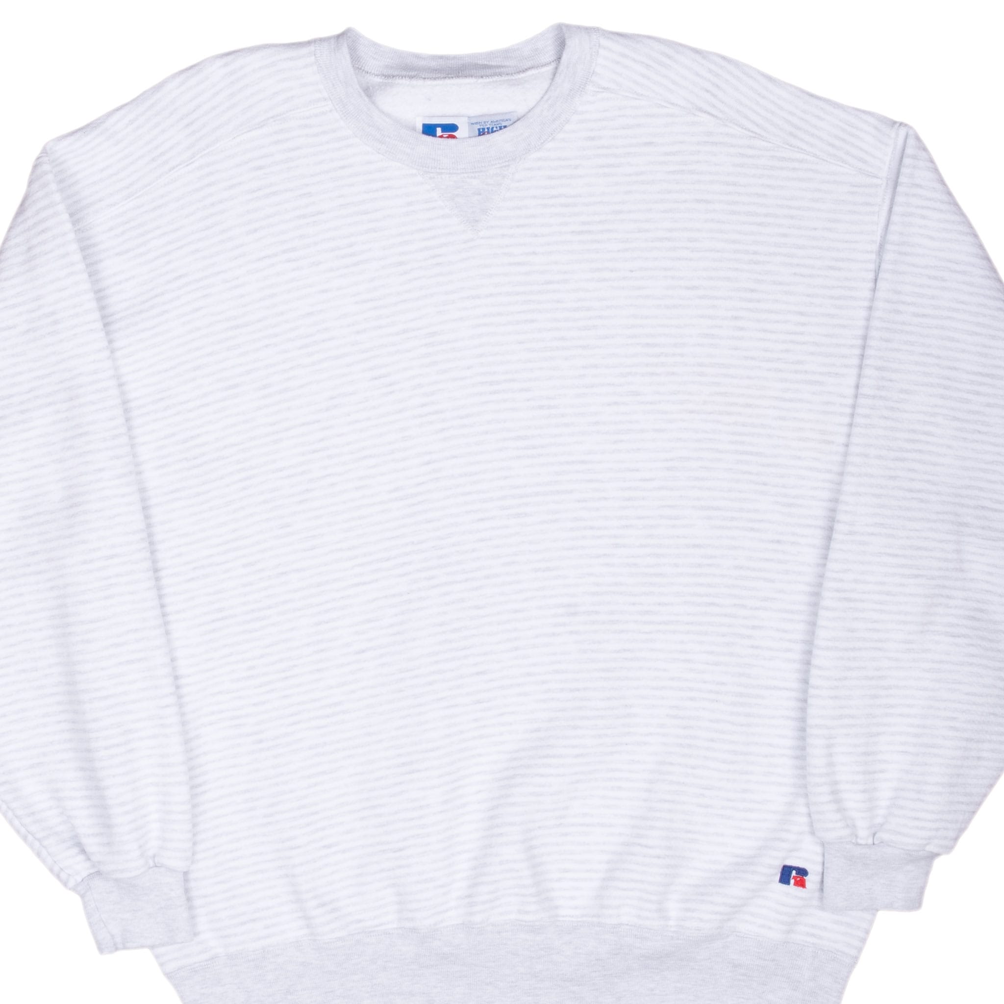 Front detail of grey striped Russell Athletic crewneck sweatshirt with logo patch near left cuff