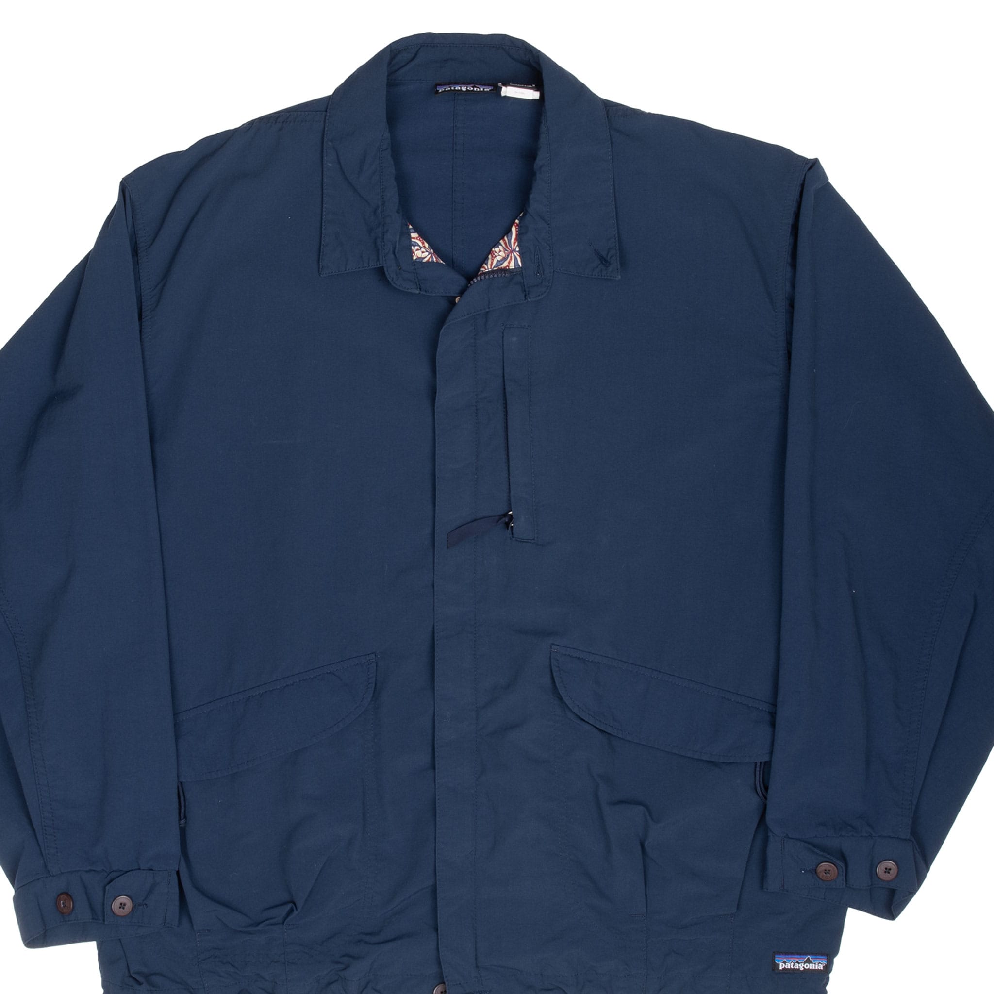 Front detail of blue Patagonia windbreaker with pointed collar, covered zipper and flap pockets