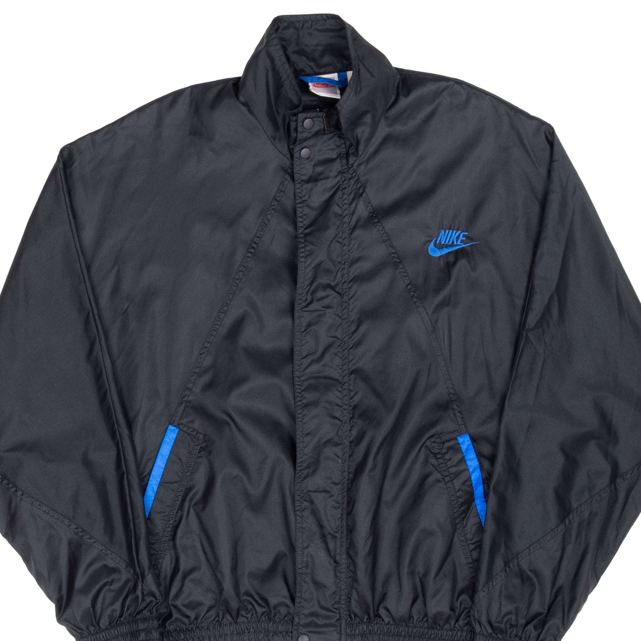 Front detail of black Nike windbreaker with blue Swoosh embroidery and blue pocket trim