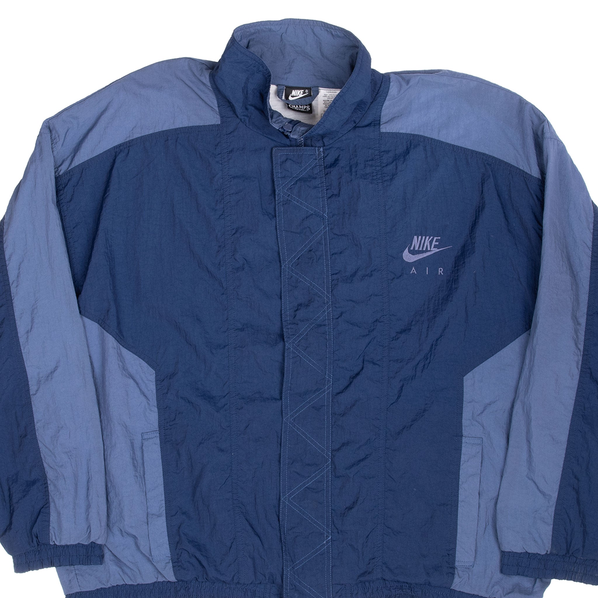 Front close-up of blue Nike Air windbreaker with curved color-block panels and storm flap
