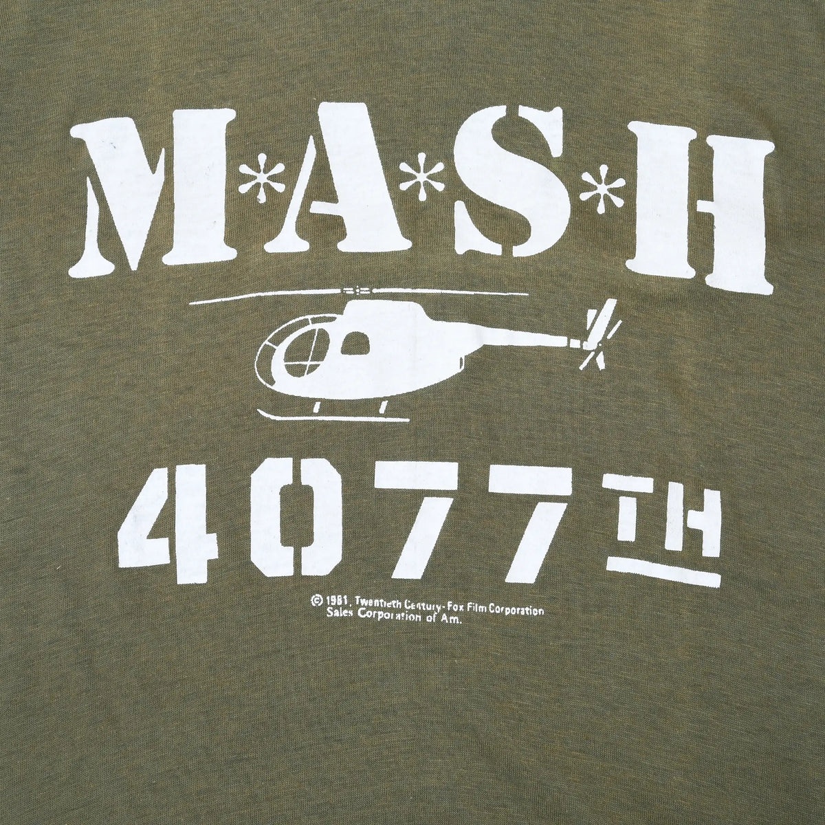 Close-up of white M*A*S*H 4077th helicopter graphic on olive green fabric