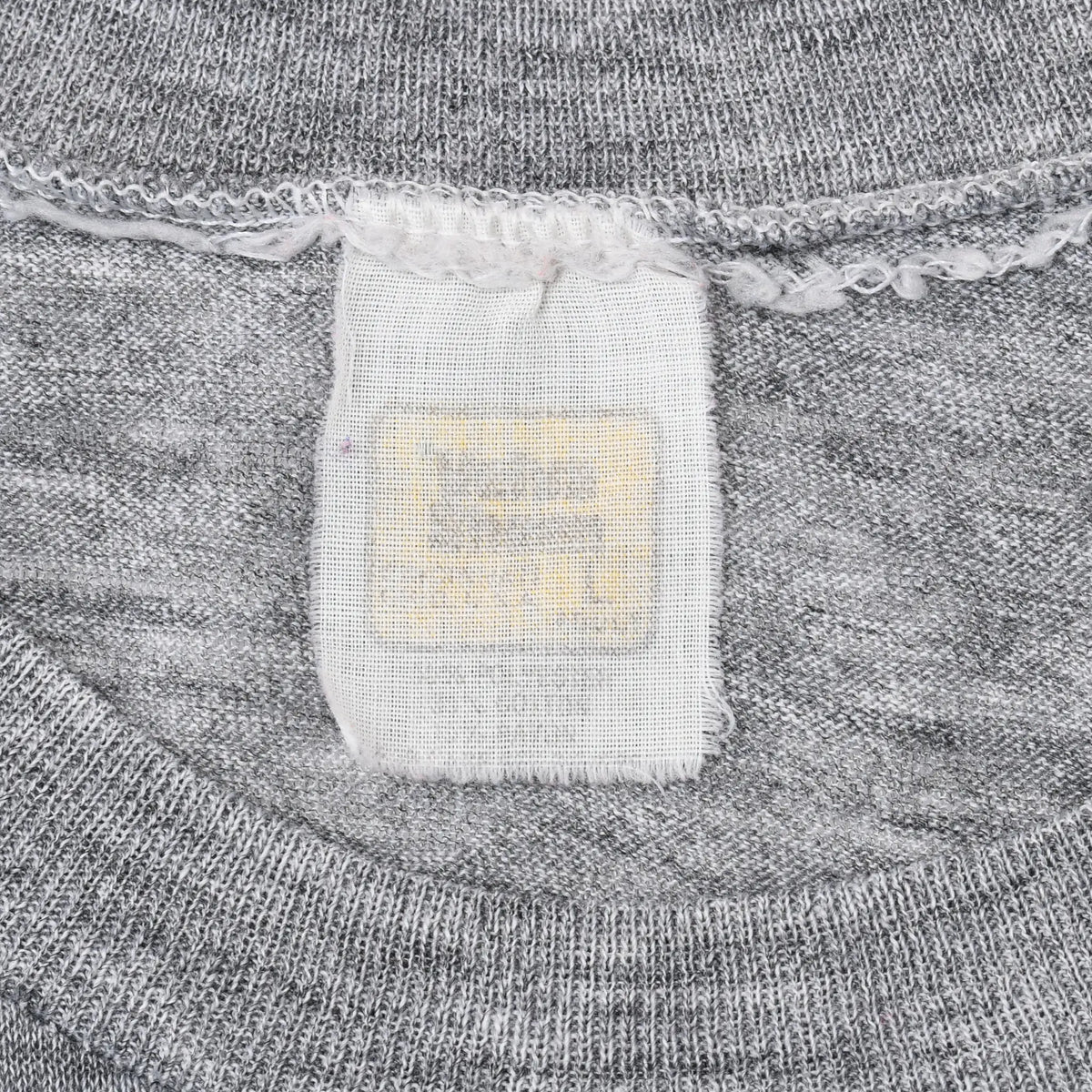 Close-up of faded neck tag and collar stitching on gray T-shirt