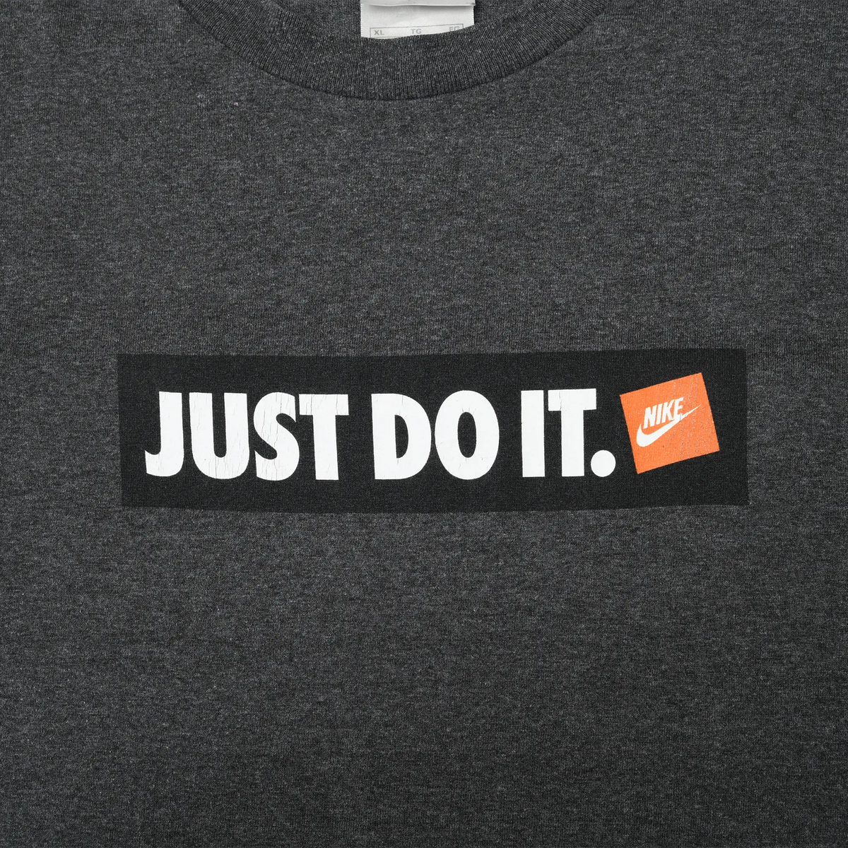 Close-up of white Just Do It lettering and orange Nike logo on black chest print