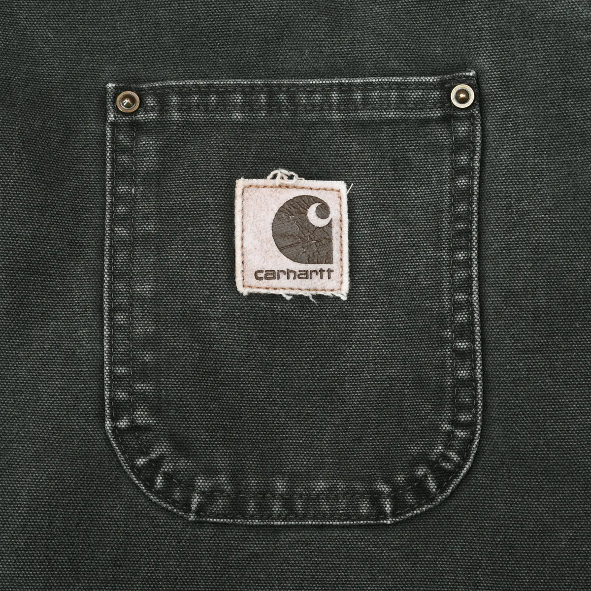 Close-up of chest pocket with stitched Carhartt logo patch and metal rivets