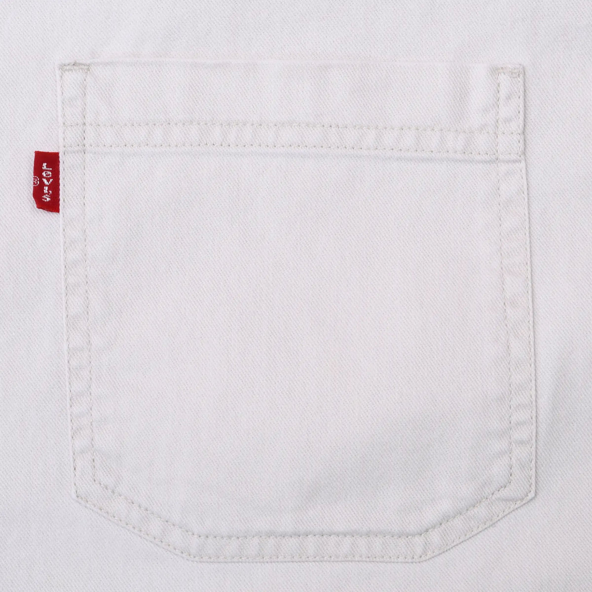 Close-up of chest pocket stitching and red Levi's tab on white denim shirt