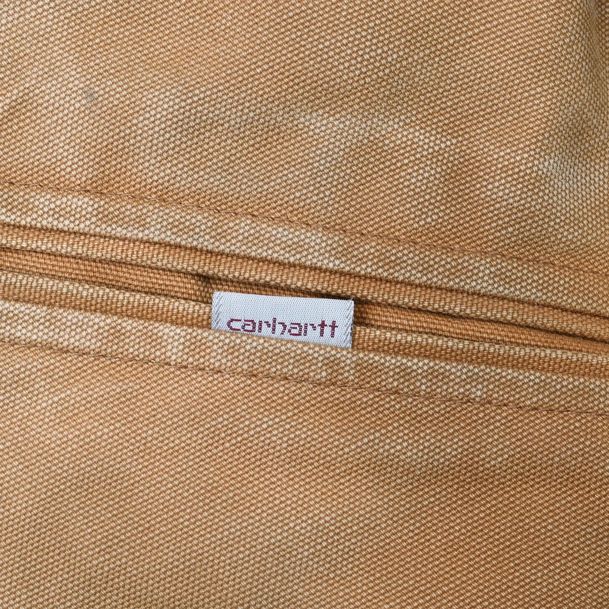 Carhartt fabric logo tab on brown zippered jacket pocket
