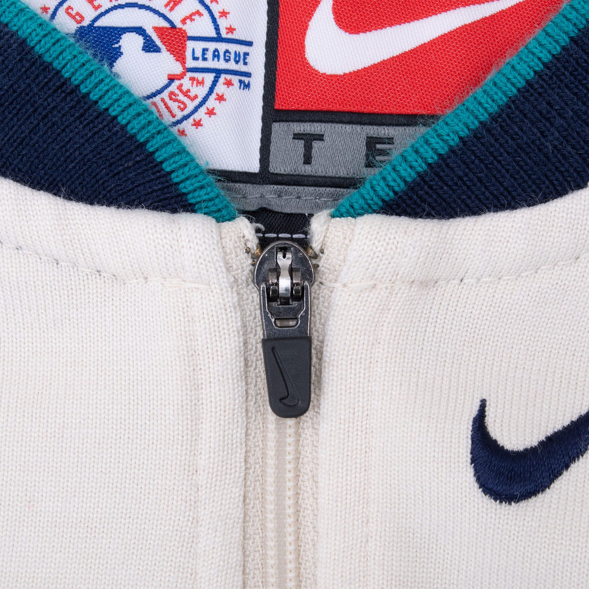 Quarter-zip collar detail with teal trim, Nike zipper pull and embroidered navy Swoosh