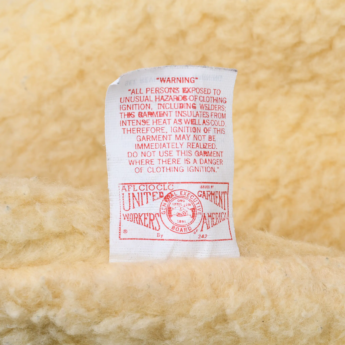 Union-made and insulation warning label inside cream sherpa-lined Carhartt vest