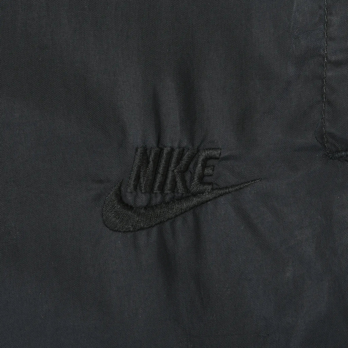 Close-up of black Nike logo embroidery on the track pants