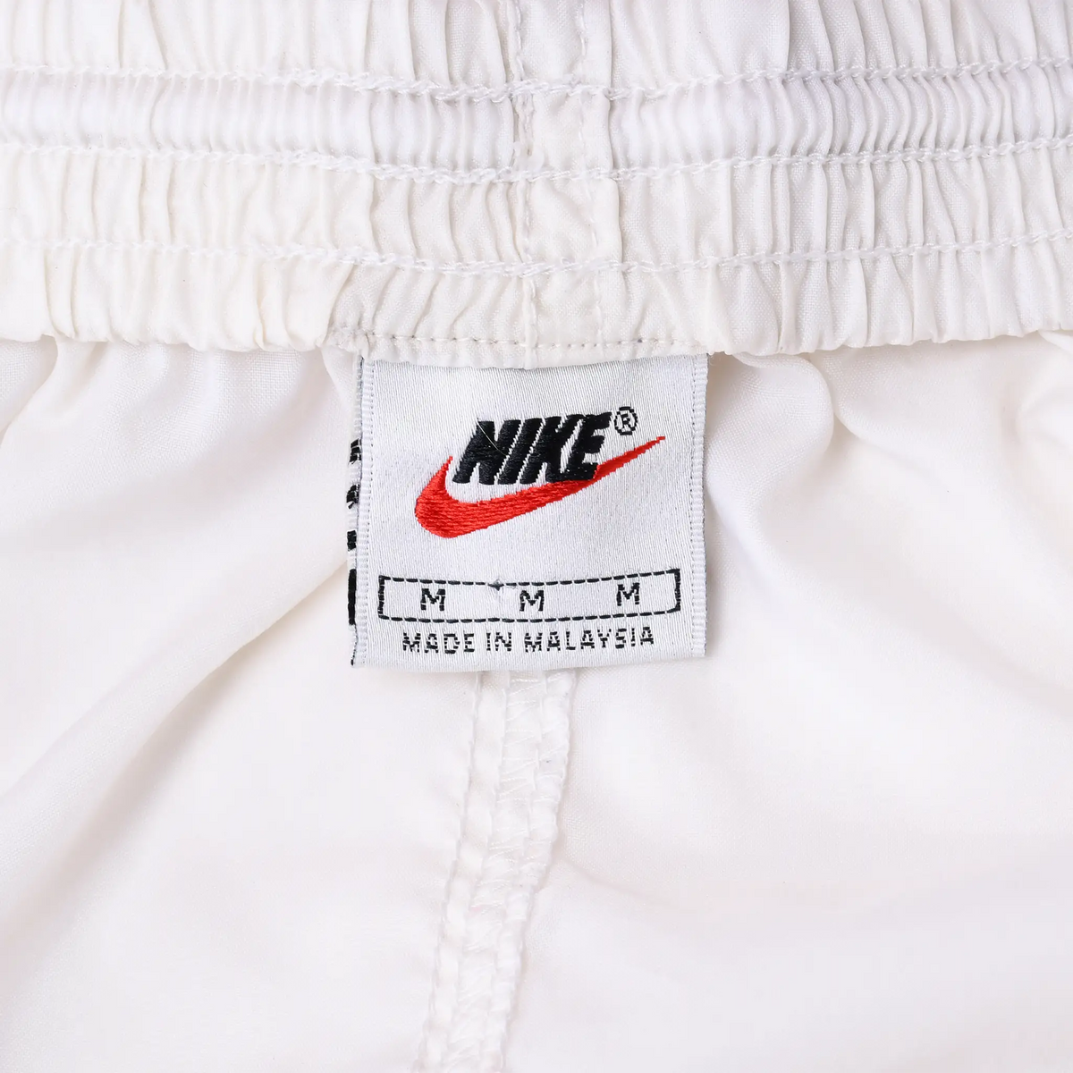Nike waistband label with black logo, red Swoosh, and medium size marking
