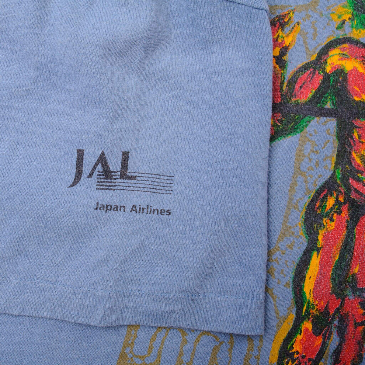 Close-up of JAL Japan Airlines sleeve print on blue Honolulu Marathon T-shirt