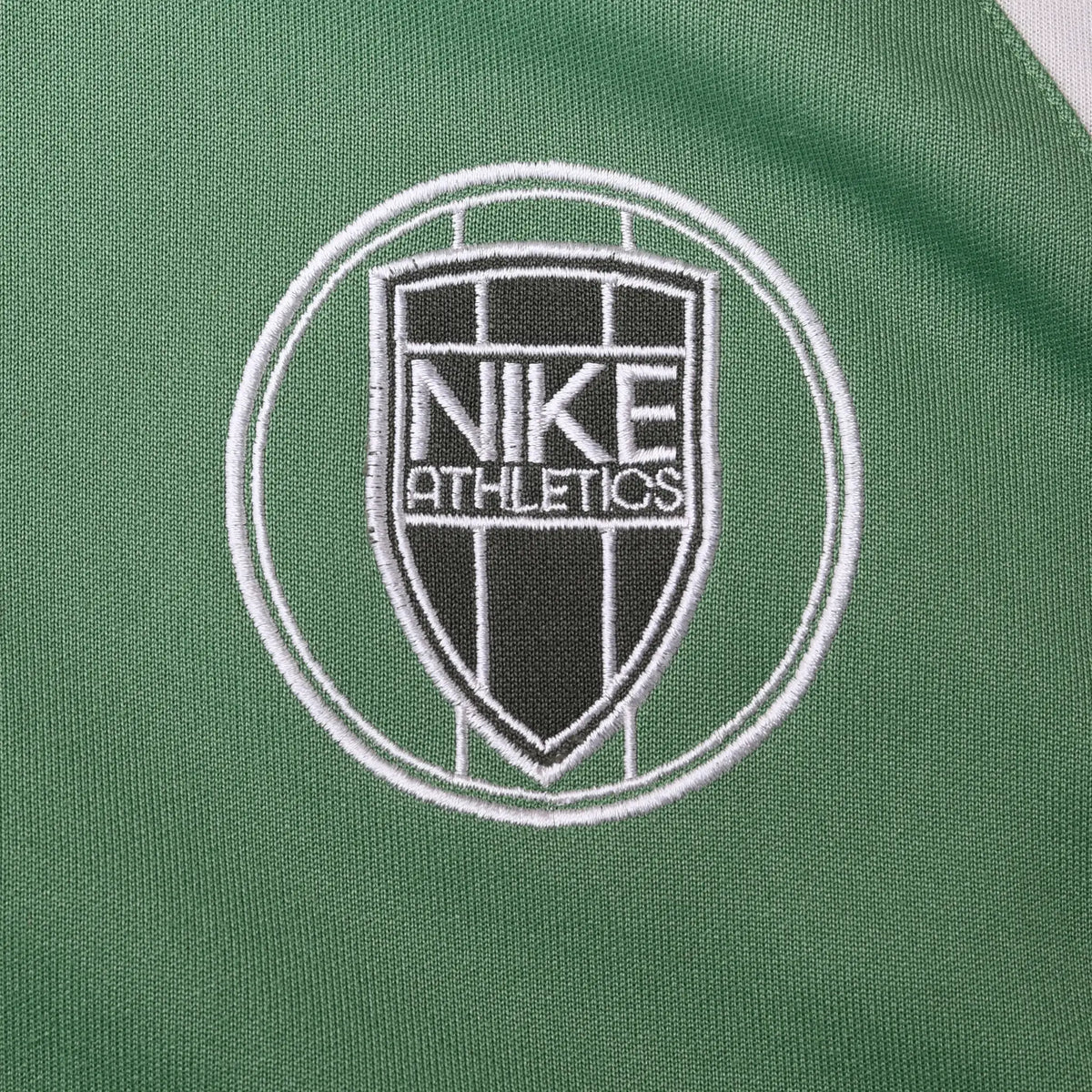 Close-up of black and white Nike Athletics crest embroidery on green jacket chest