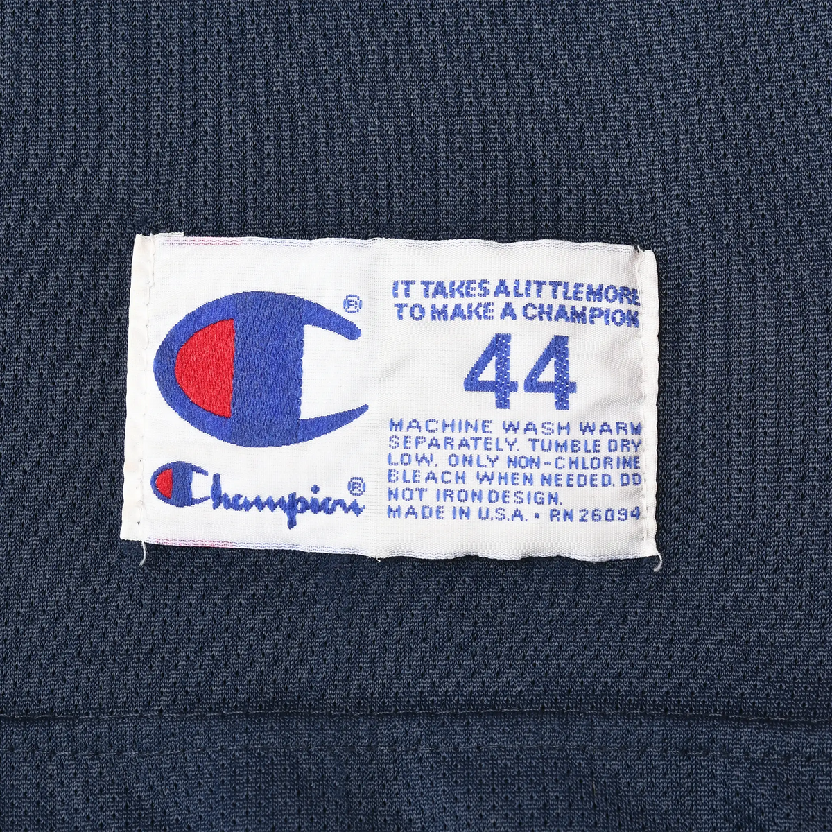 Close-up of Champion size 44 care label sewn inside navy basketball jersey