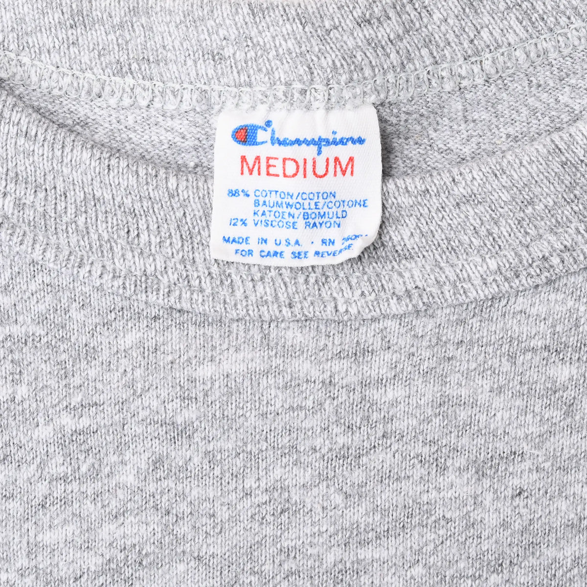 Close-up of Champion Medium neck tag on gray T-shirt