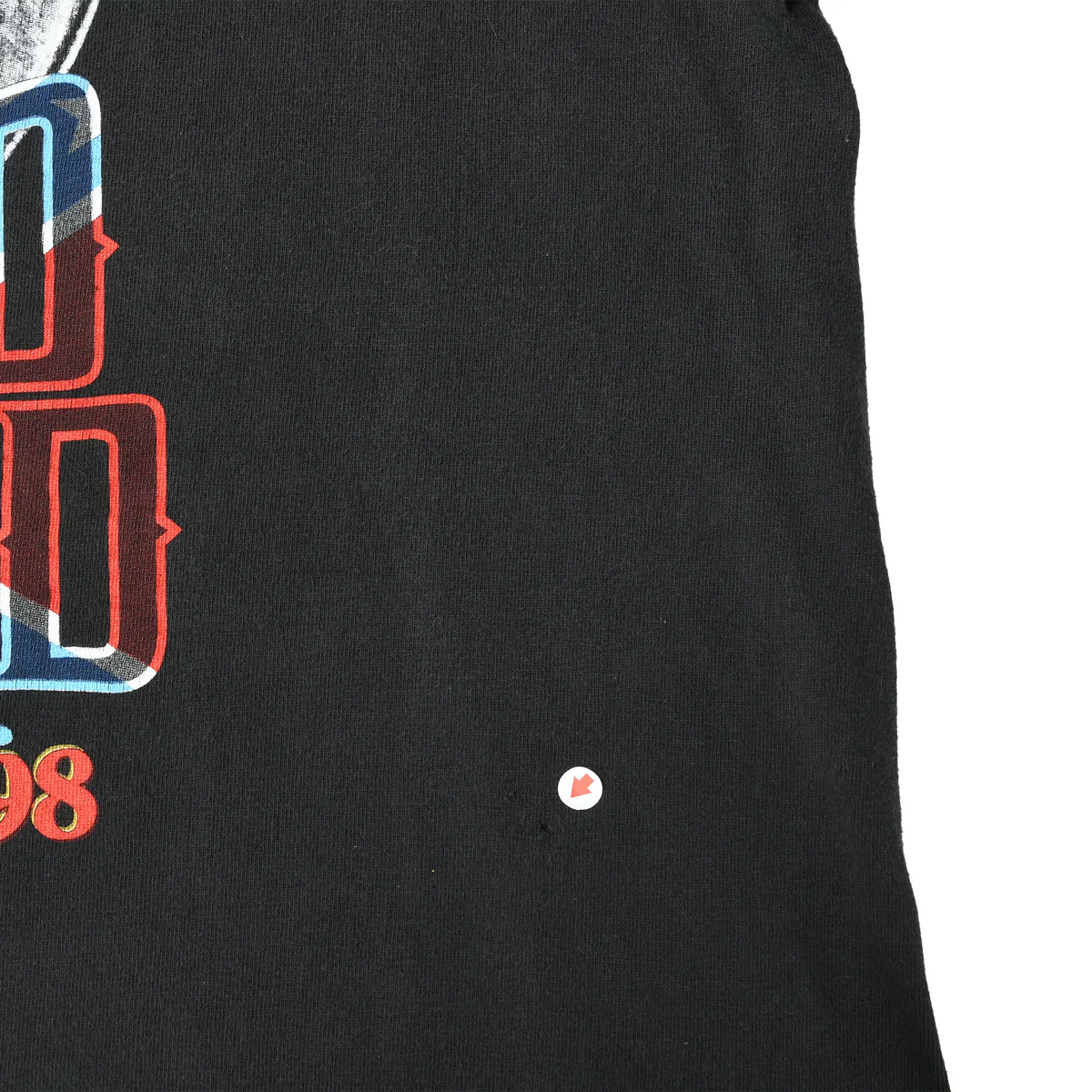 Close-up of black front fabric beside the Lynyrd Skynyrd print, with a small spot marked by an arrow