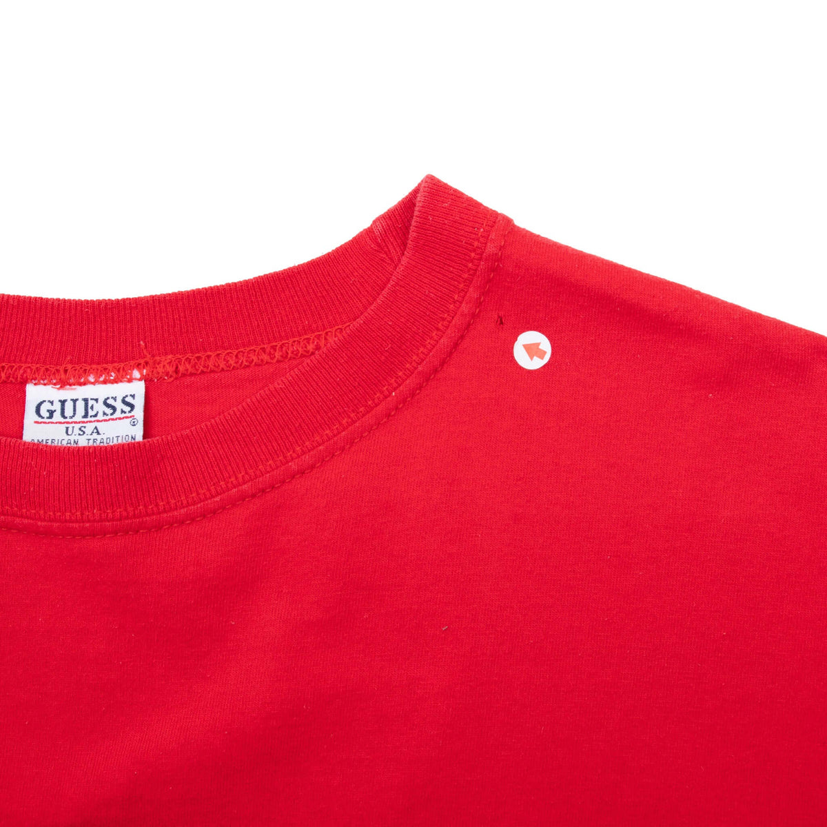 Close-up of red T-shirt collar, Guess label, and small mark near right shoulder