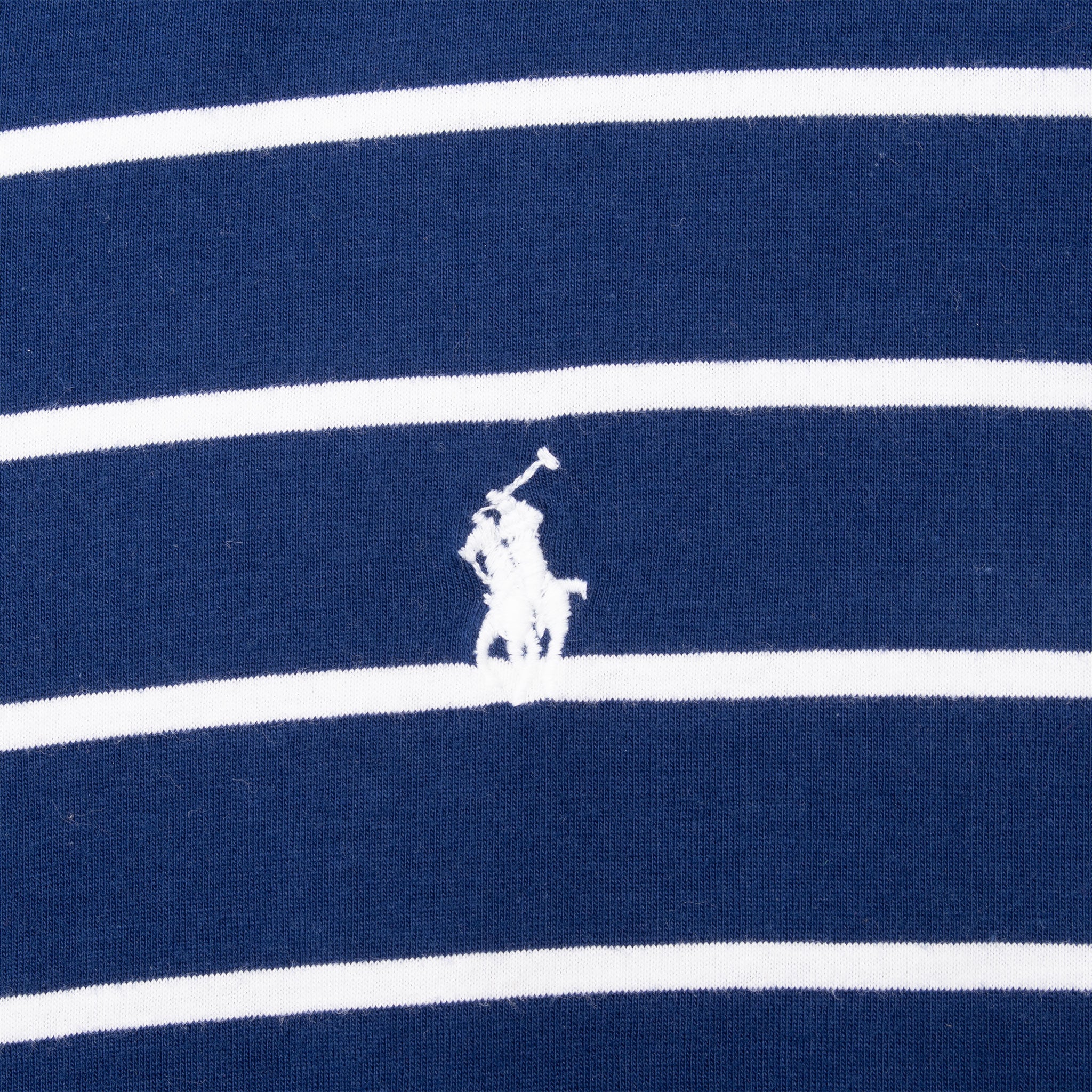 Close-up of white Polo pony embroidery on navy and white striped fabric
