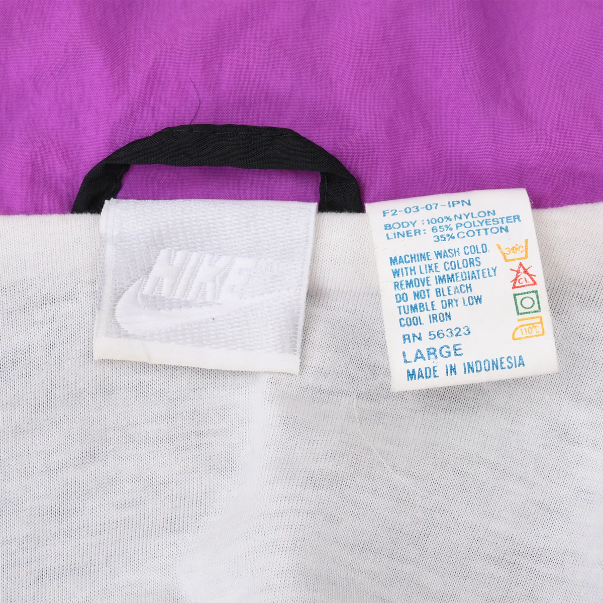 Nike neck and care labels inside windbreaker showing size Large against purple and white lining