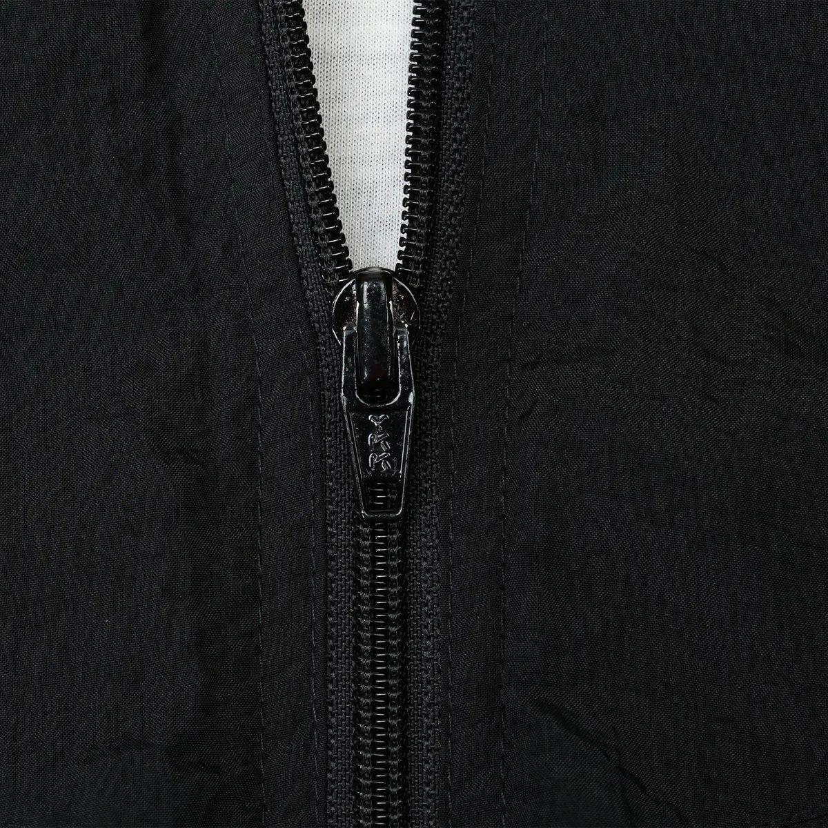 Close-up of black front zipper and surrounding fabric on Nike windbreaker