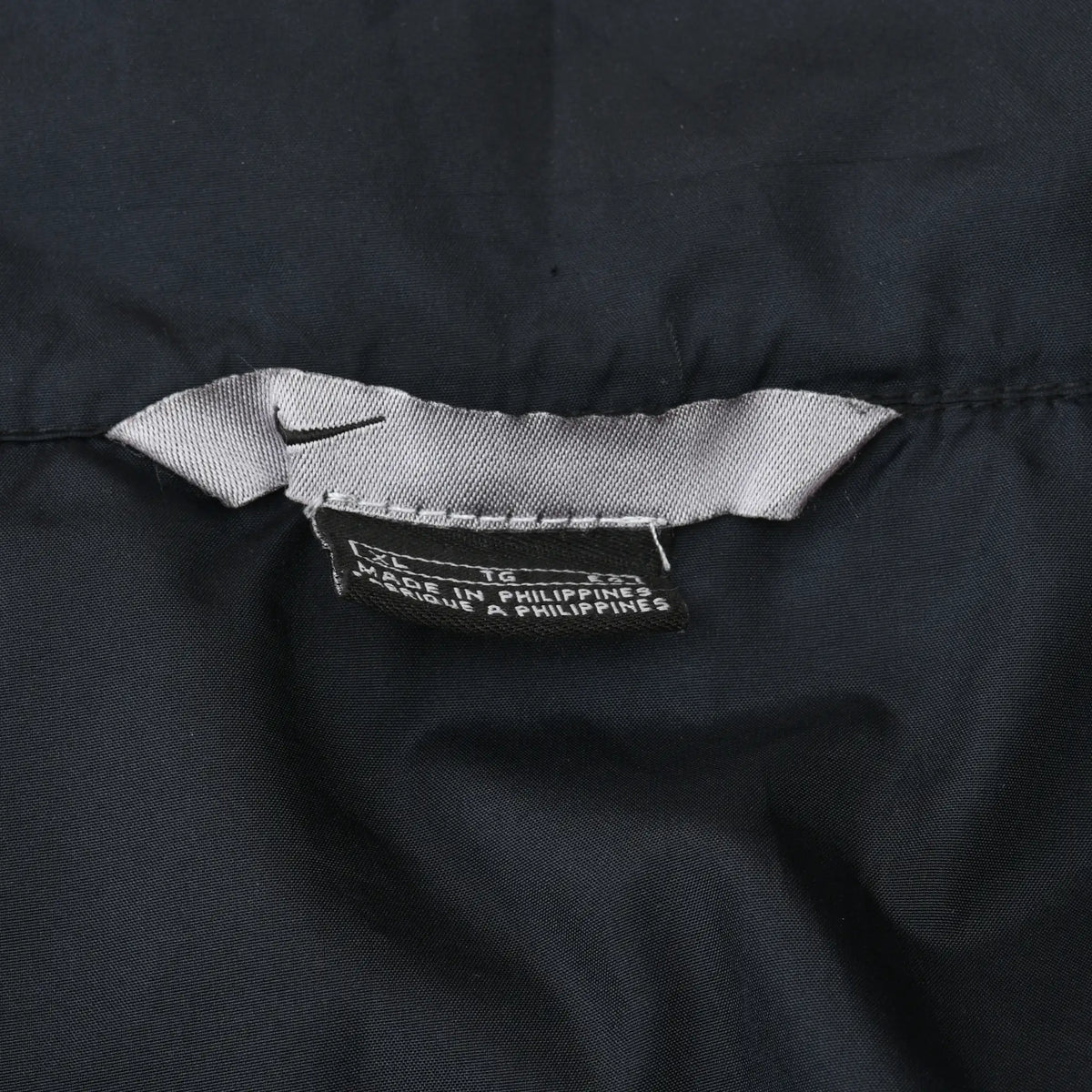 Close-up of Nike neck label and Made in Philippines tag inside black windbreaker jacket
