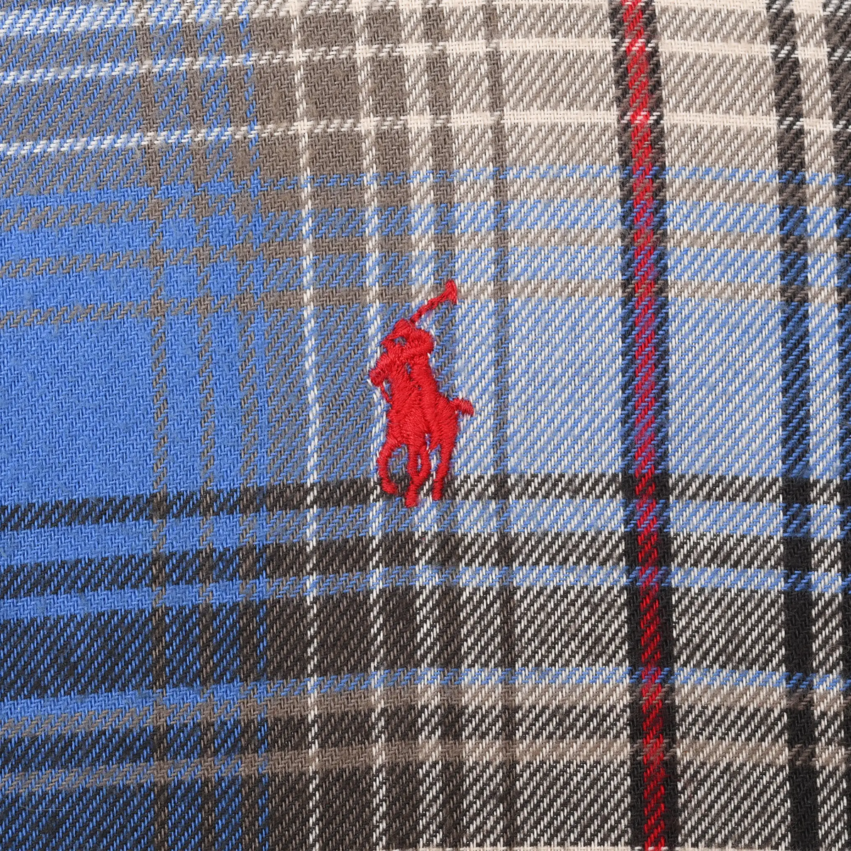 Close-up of red Ralph Lauren polo player embroidery on blue and grey plaid fabric