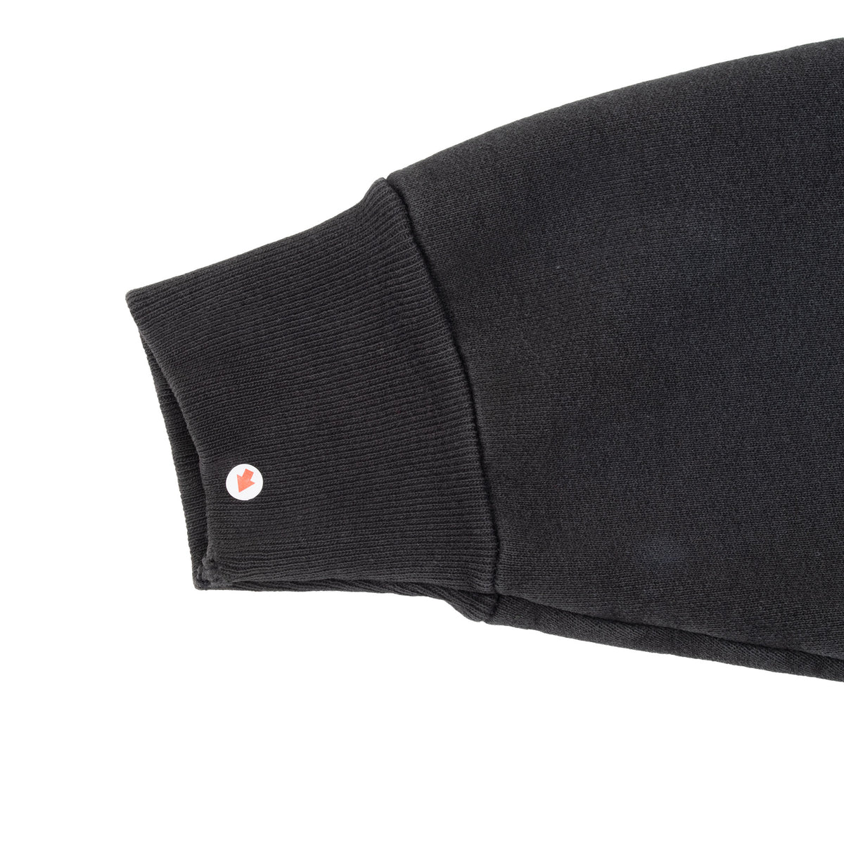 Black sweatshirt ribbed cuff and sleeve seam detail with small circular marker