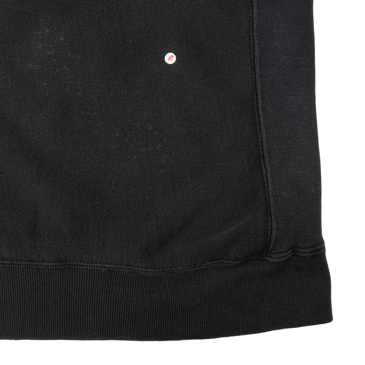 Black sweatshirt lower back and ribbed hem detail with small circular marker