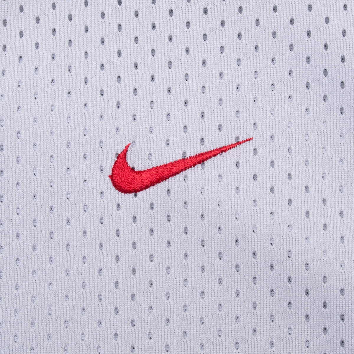 Close-up of red embroidered Nike Swoosh on grey mesh fabric
