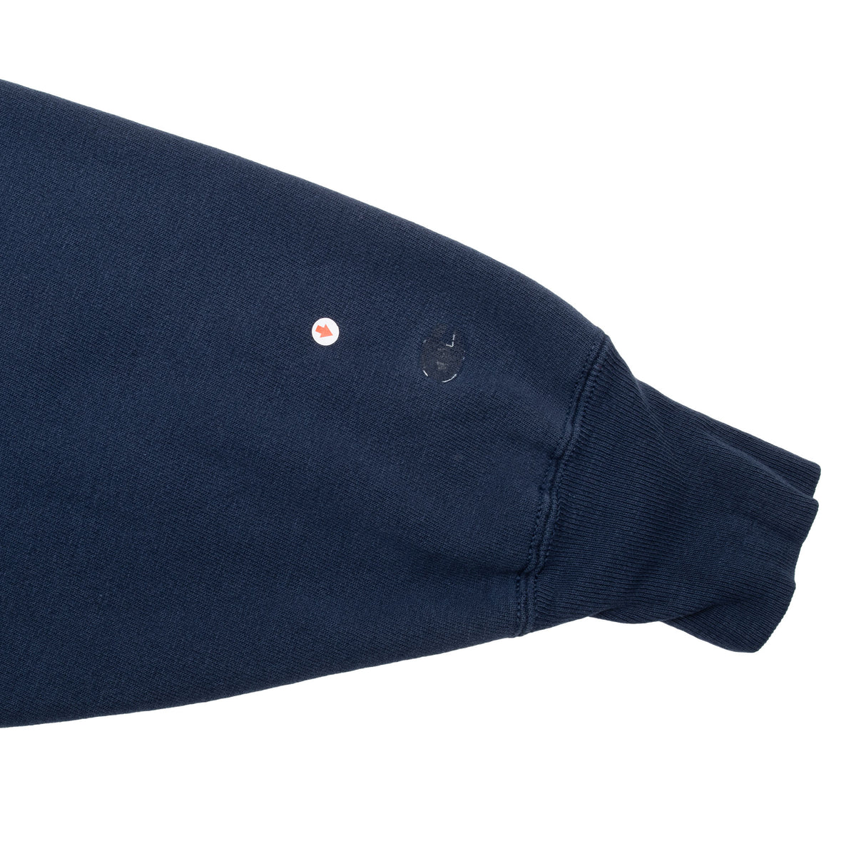 Close-up of navy sweatshirt sleeve near cuff showing a small hole and worn spot