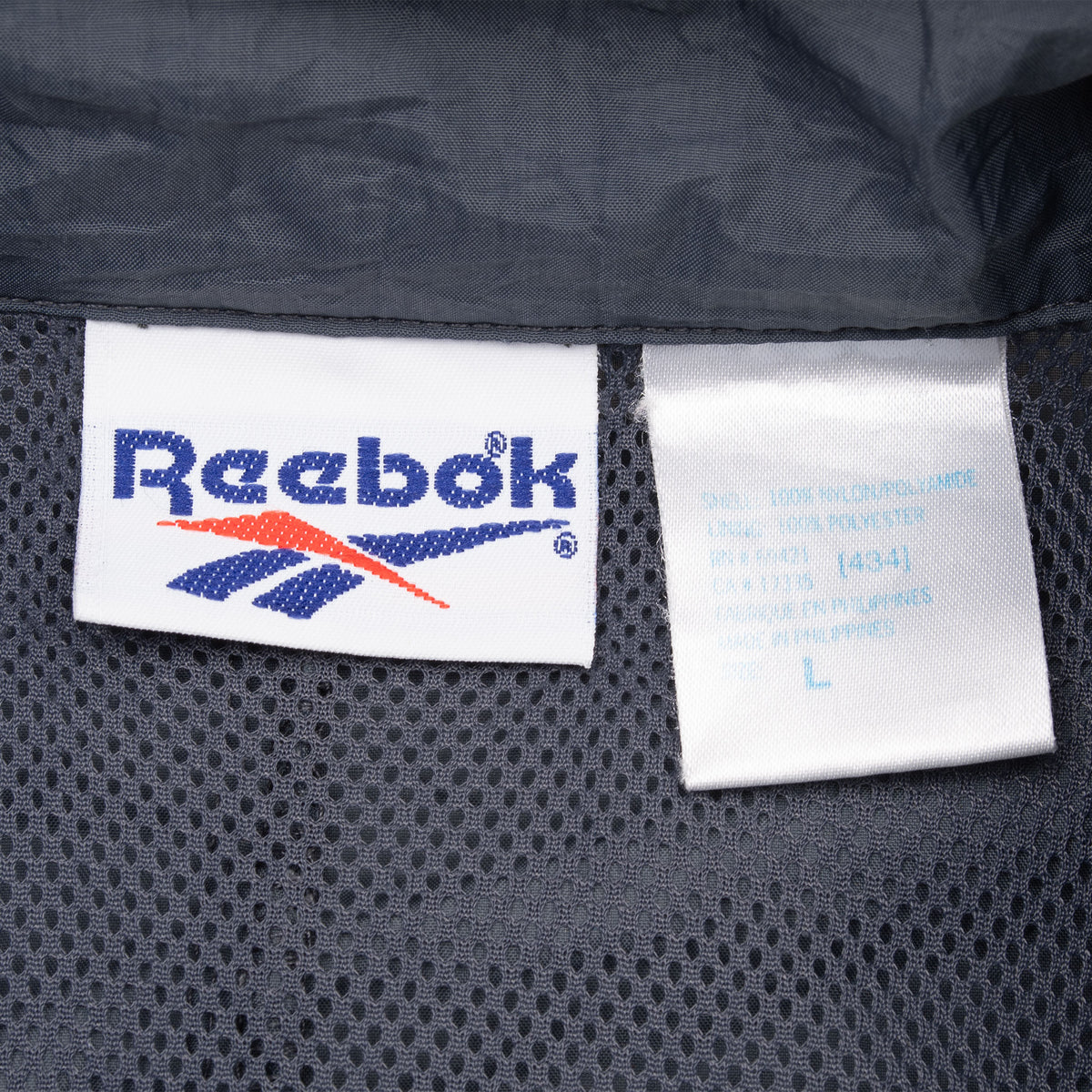Close-up of Reebok neck label and adjacent garment tag inside jacket