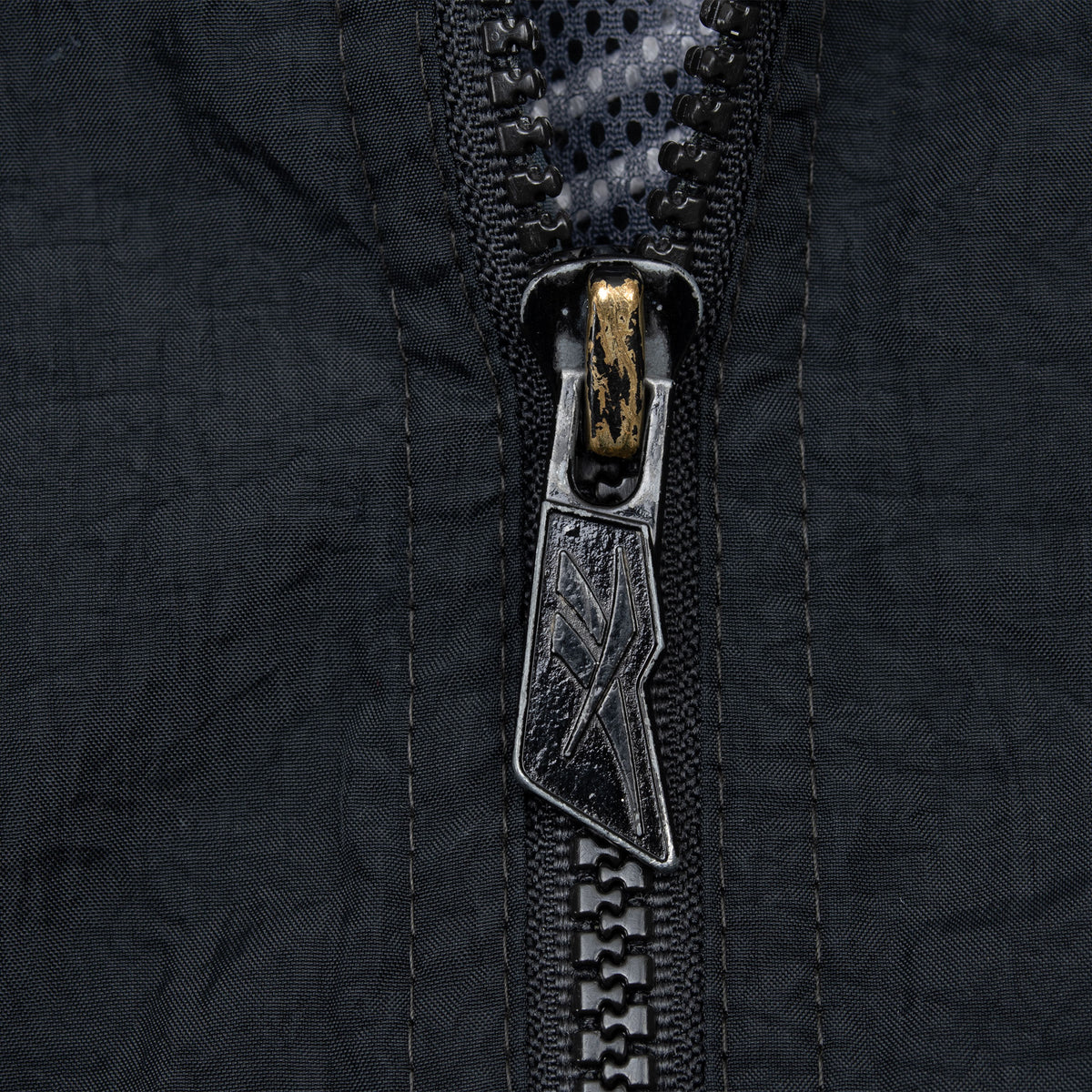Close-up of black Reebok logo zipper pull on jacket