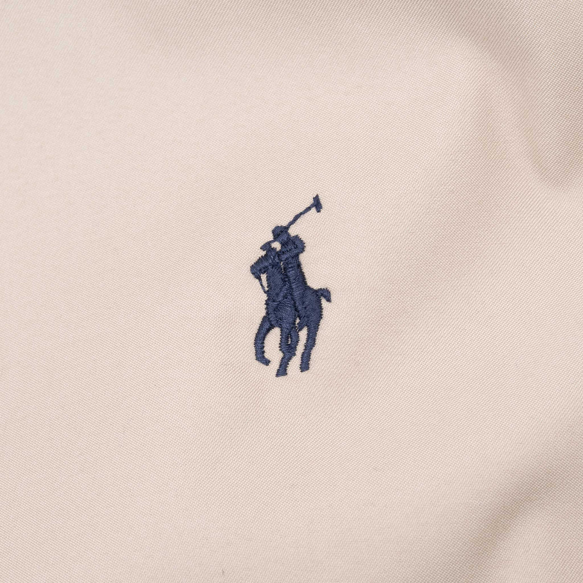 Close-up of navy Polo pony embroidery on beige jacket chest