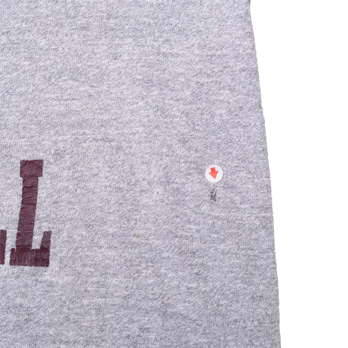 Close-up of small mark on gray shirt front, indicated by an arrow