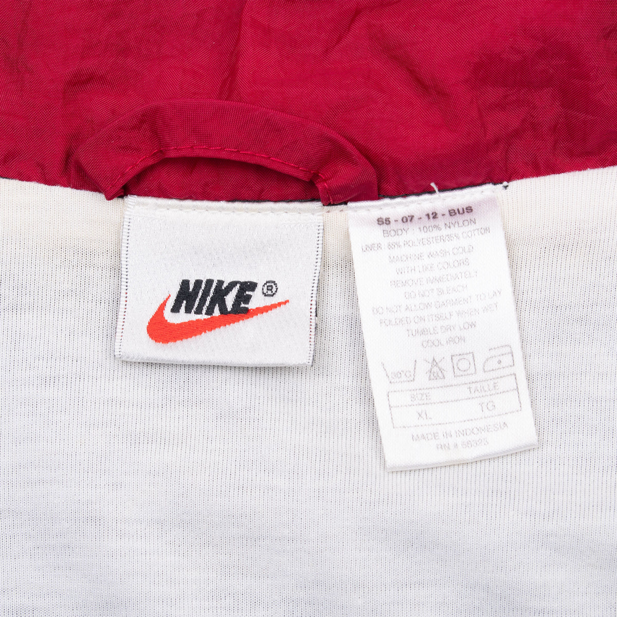 Interior Nike neck label and care tag against red and white lining