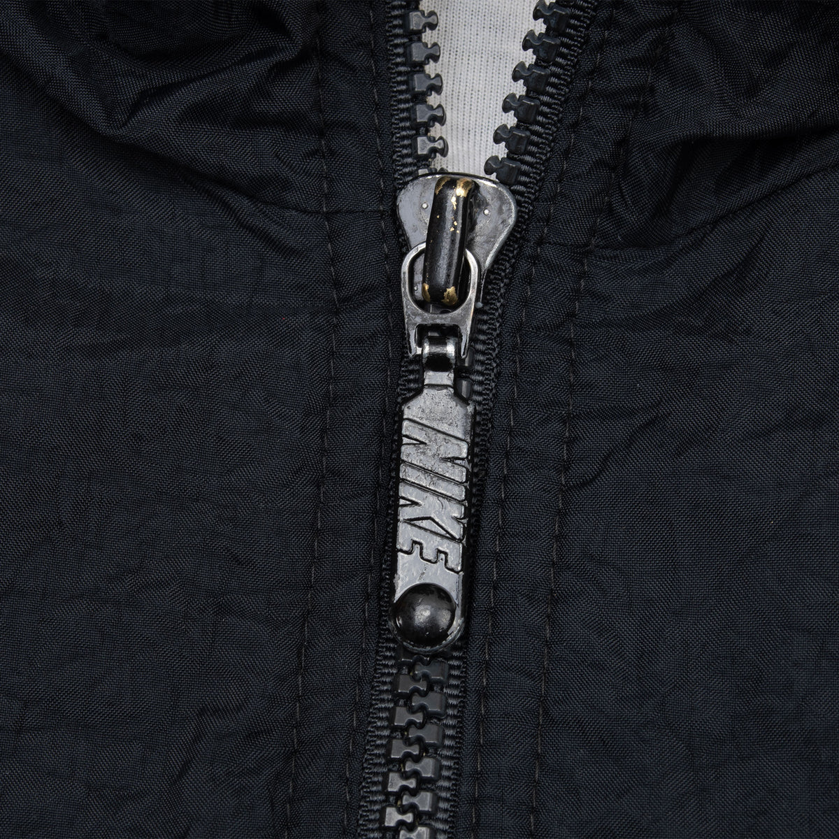 Close-up of Nike-branded zipper pull on black windbreaker