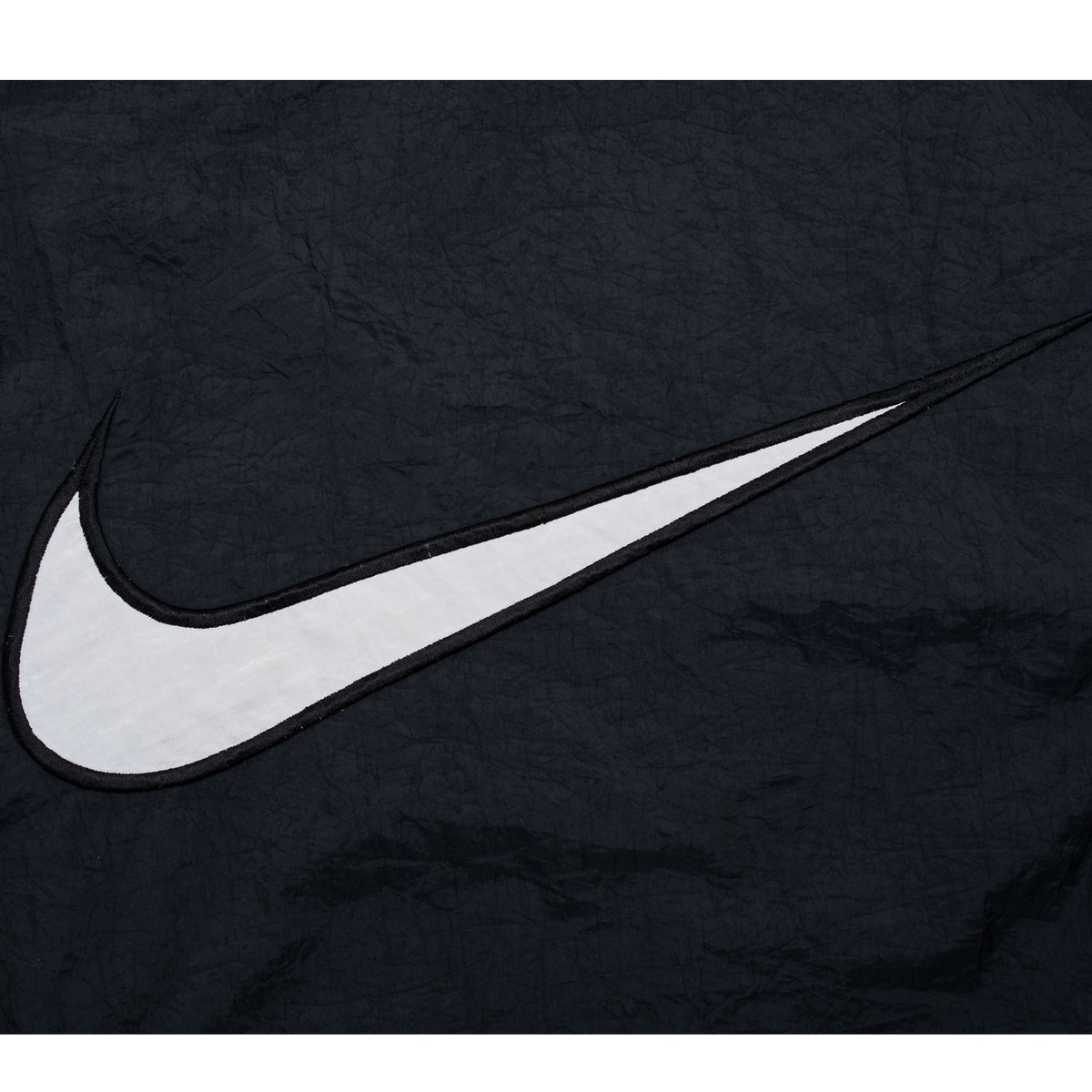 Close-up of large white Nike Swoosh appliqué on black back panel