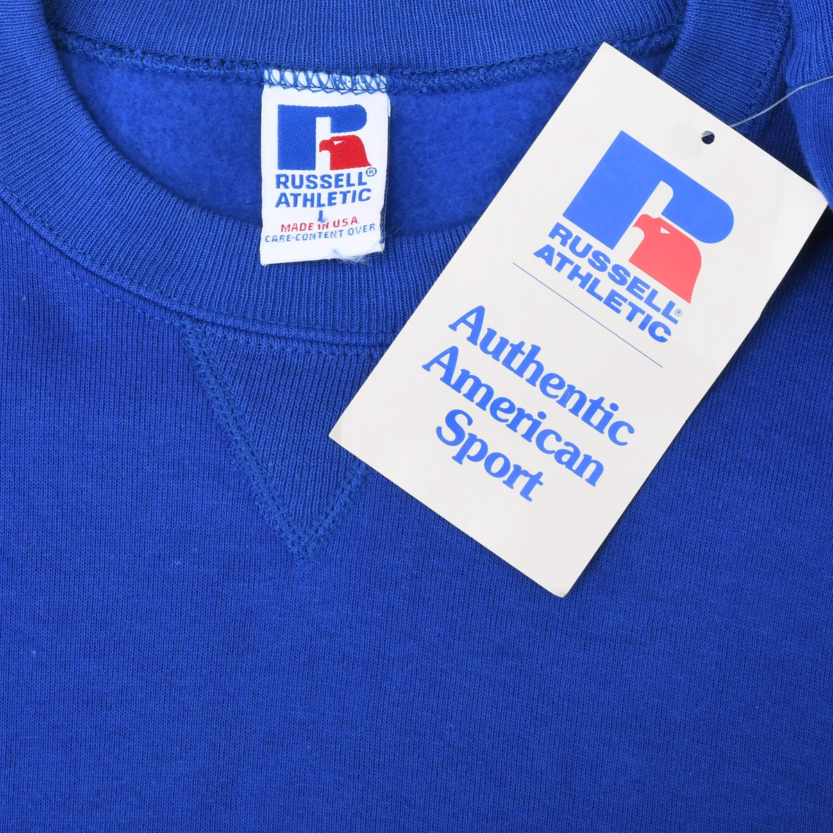 Close-up of Russell Athletic neck label and Authentic American Sport hangtag on blue sweatshirt