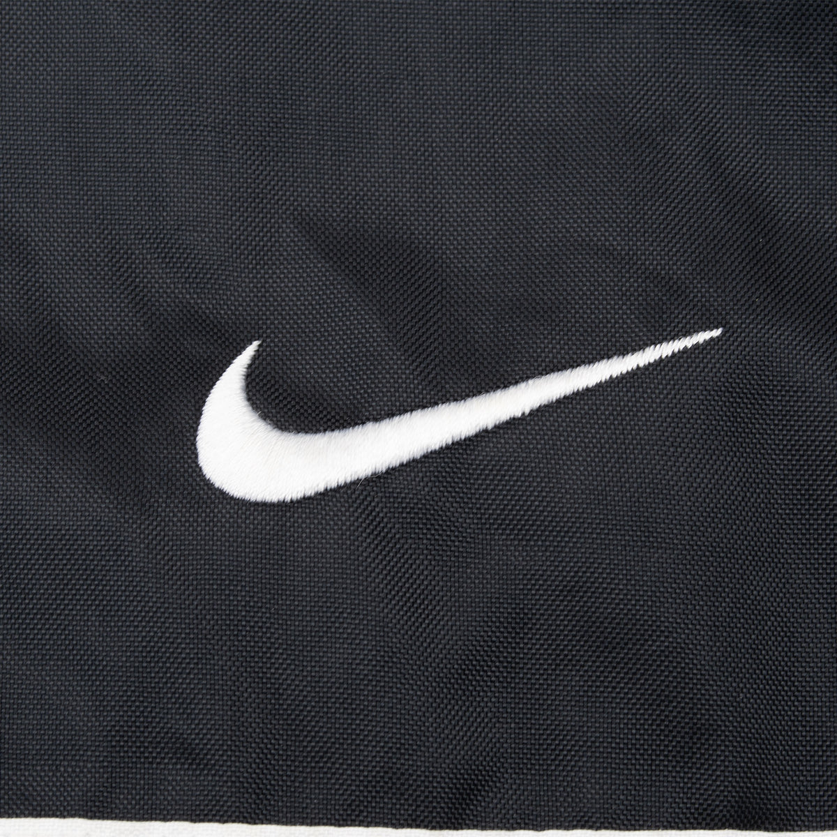 White embroidered Nike Swoosh detail on black jacket chest