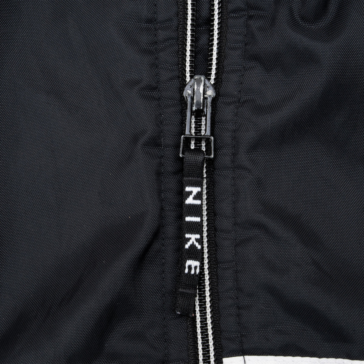 Close-up of front zipper with black Nike logo pull tab