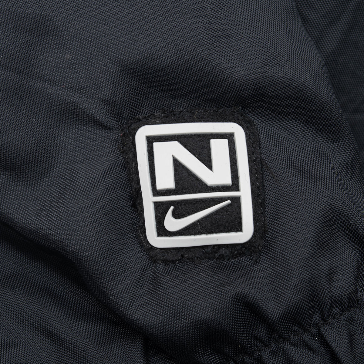 Black-and-white Nike logo patch detail near jacket cuff