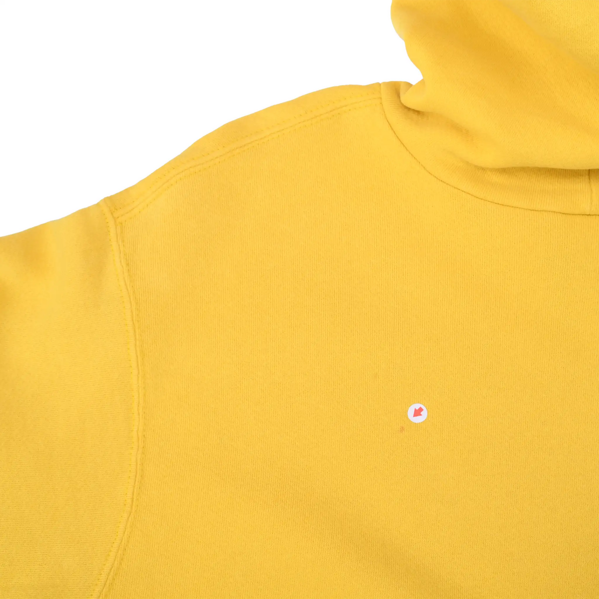Close-up of yellow hoodie's upper back and shoulder with a small circular mark