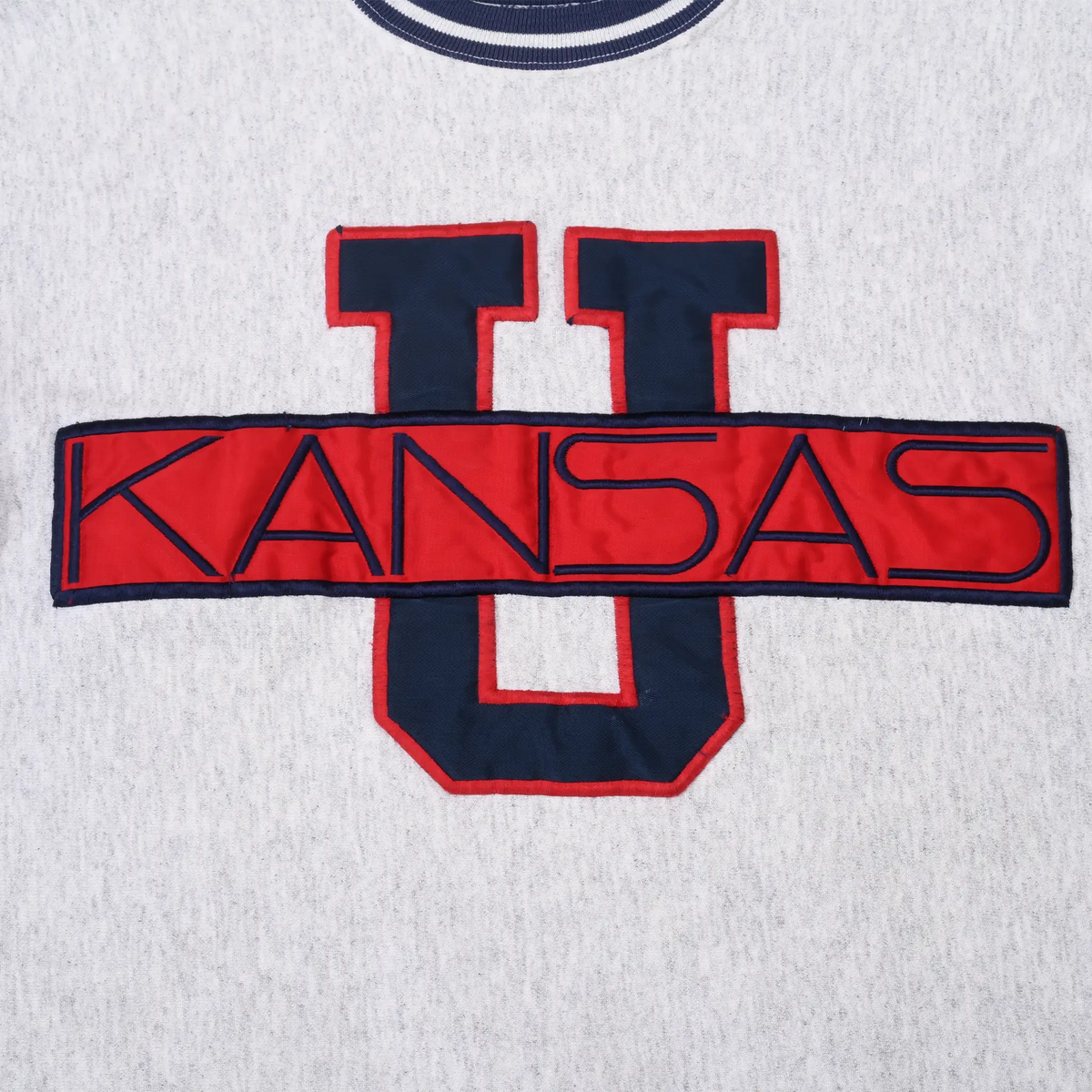 Close-up of navy and red Kansas U appliqué on grey sweatshirt front