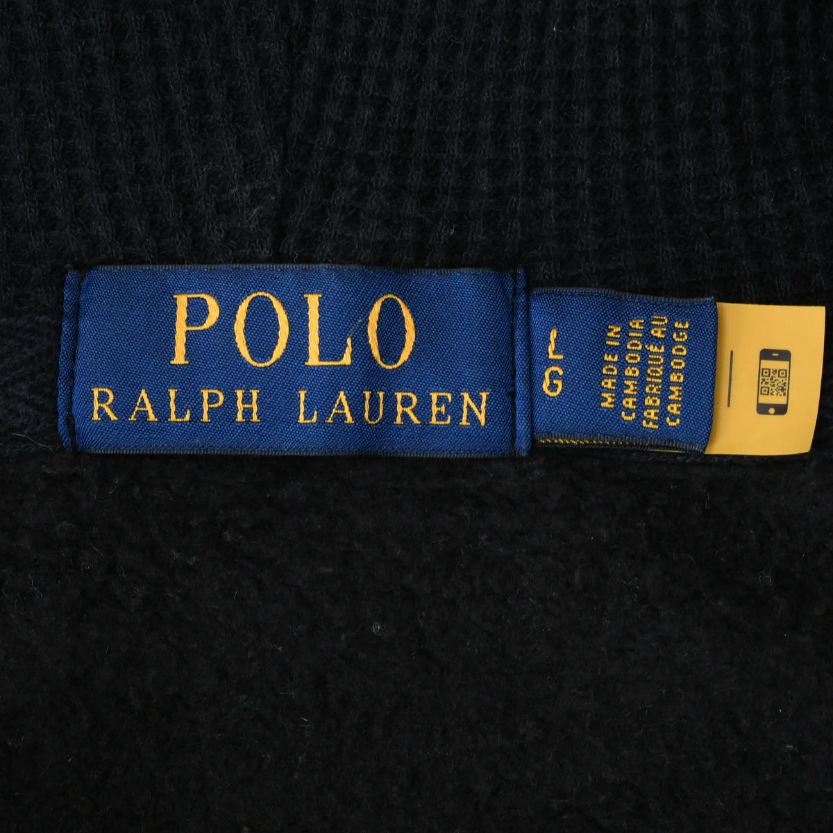 Close-up of blue Polo Ralph Lauren neck label and attached care tag inside black hoodie