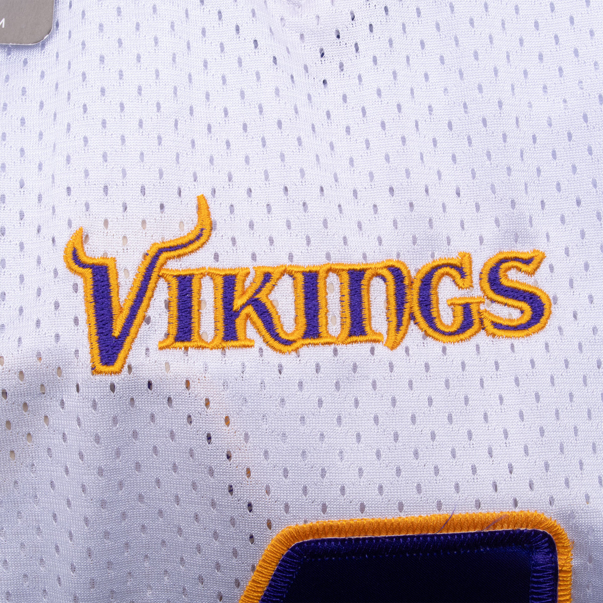 Close-up of purple and gold Vikings embroidery on white mesh jersey