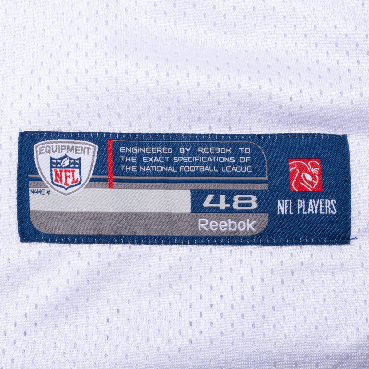 Close-up of Reebok NFL Equipment size 48 hem label on white mesh fabric