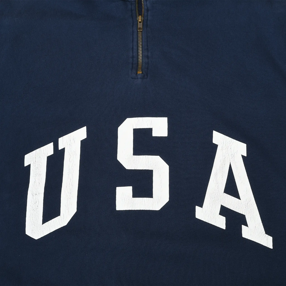 Close-up of white USA chest print and quarter zipper on navy sweatshirt