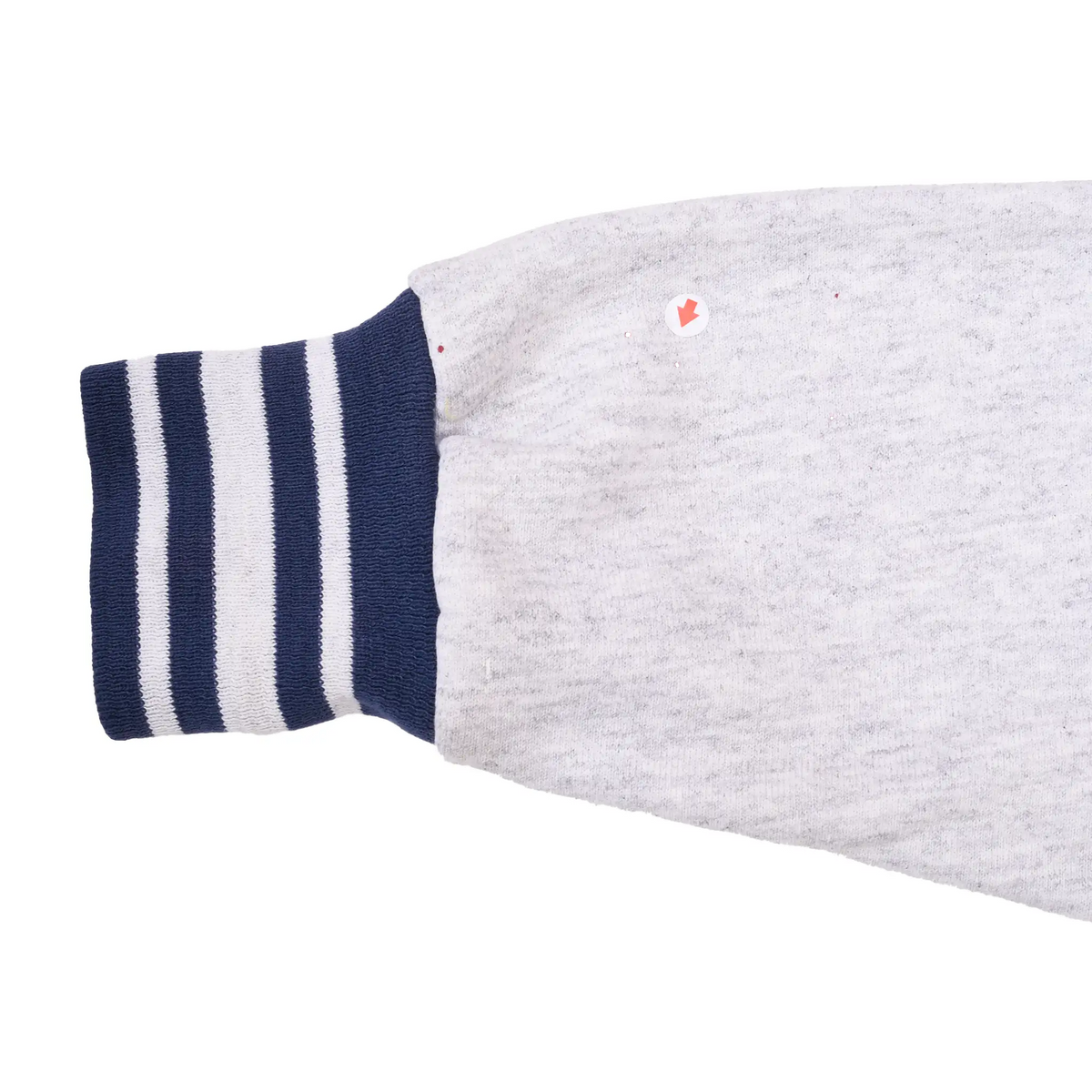 Grey sweatshirt sleeve detail with navy striped cuff and small red marks near seam