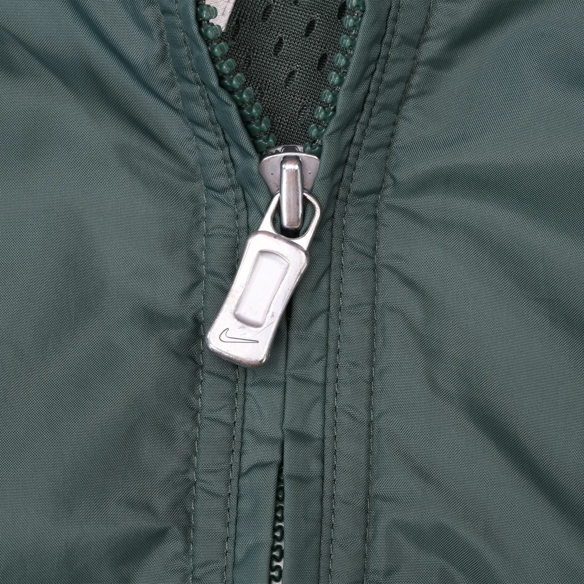 Close-up of silver zipper pull and stitching on green Nike windbreaker