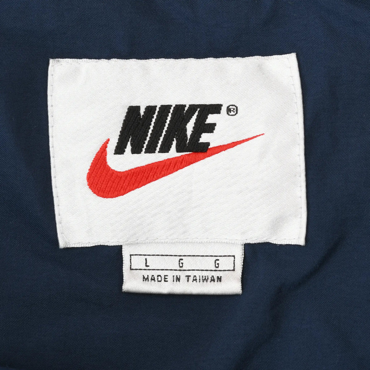 Nike neck label with black logo, red Swoosh, and L size marking