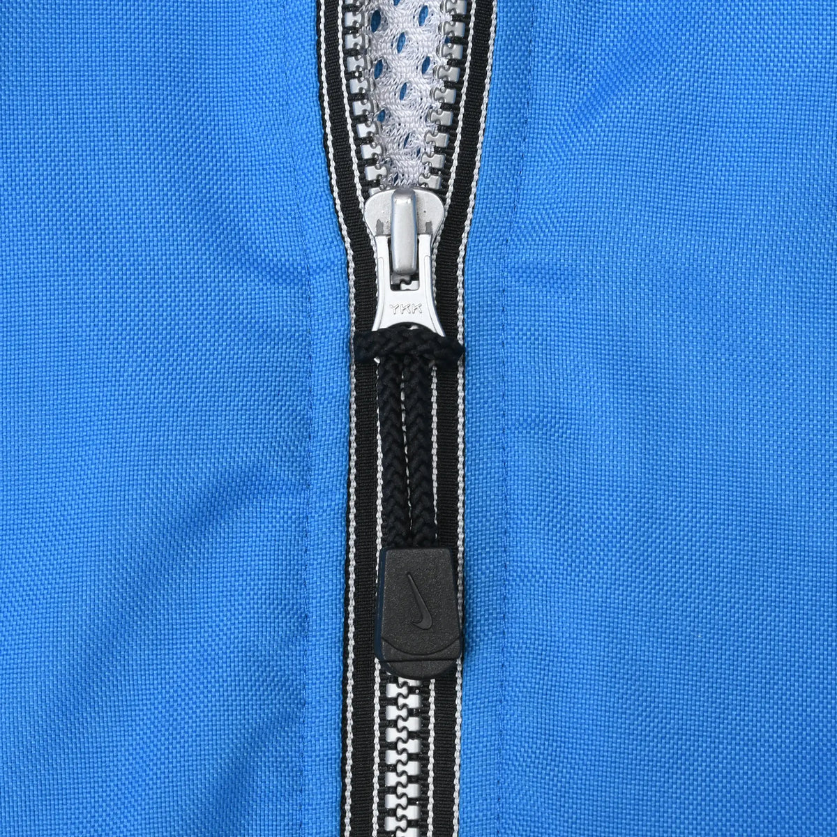 Close-up of front zipper and black Nike Swoosh pull tab on blue jacket